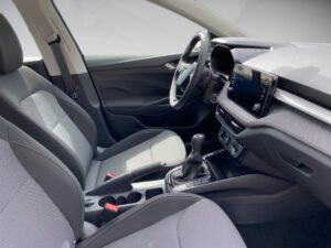 Innenraum eines modernen Autos, graue Sitze, Touchscreen-Display, Schalthebel, helle Farben.