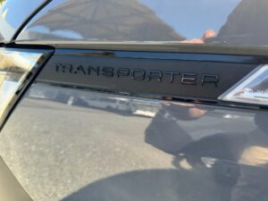 Nahaufnahme des Wortes "Transporter" auf einem grauen Fahrzeug mit reflektierender Oberfläche.