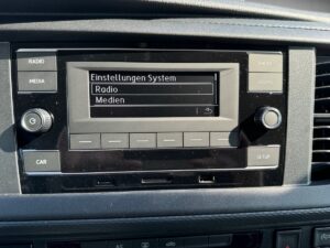 Das Bild zeigt ein Autoradio-Display mit den Optionen "Radio" und "Medien".