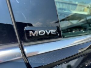 Schwarzes Auto mit "MOVE"-Abzeichen an der Tür, glänzende Oberfläche, Reflexionen sichtbar.