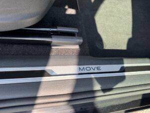 Eine Autotürschwelle mit der Aufschrift "MOVE", silberne Verkleidung, schwarze Bodenmatte.