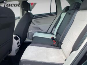 Rücksitzbereich eines Autos mit schwarzen Sitzen und weißen Bezügen. Elegantes Interieur.