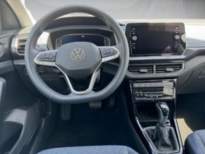 Interieur eines Volkswagen: Lenkrad und digitale Anzeige, schwarzes Armaturenbrett.