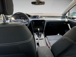 Auto-Innenraum mit dunklem Interieur, modernem Armaturenbrett und gesteppten Sitzen.