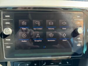 Das Bild zeigt ein Auto-Infotainment-System mit Touchscreen und mehreren App-Symbolen in Schwarz.