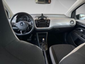 Innenraum eines VW mit grauem Armaturenbrett, schwarzem Lenkrad und grauen Sitzen.