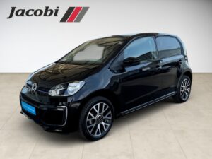 Kompakter schwarzer VW Up! mit Glanzfinish, geparkt in einem Showroom. Logo "Jacobi" an der Wand.