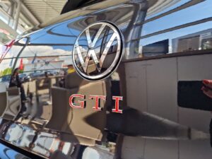 Rückseite eines schwarzen VW GTI im Sonnenschein, reflektierende Oberfläche, VW-Logo.