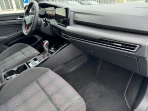 Innenraum eines Autos mit grauen Sitzen, roten Akzenten und modernem Lenkrad, Armaturenbrett.