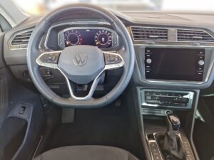 Lenkrad eines VW-Autos, elegante Anzeige, schwarzes Interieur mit silbernen Akzenten.