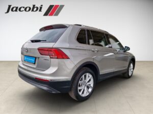 VW Tiguan in Silber, seitlich von hinten. Jacobi-Logo oben links. Glänzende Lackierung.