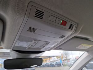 Ein Auto-Innenraum zeigt ein graues Bedienfeld mit Lüftungsschlitzen und Notrufknopf auf der Decke.