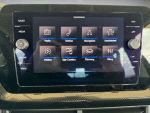 Touchscreen eines Autos mit Optionen wie Radio, Telefon, Navigation und Fahrzeugsteuerung.