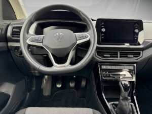 Lenkrad eines Volkswagen mit grauen Akzenten und einem Touchscreen-Display im modernen Armaturenbrett.