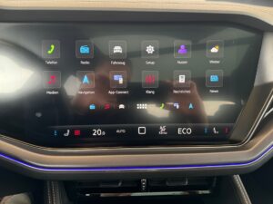 Eine Person bedient ein Auto-Infotainment-System mit bunten Symbolen und einem ECO-Modus.