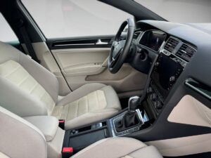 Innenraum eines modernen Autos, beige Sitze, schwarzes Armaturenbrett, Touchscreen, elegantes Design.