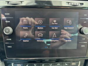 Ein Touchscreen in einem Auto, der verschiedene Funktionen wie Radio, Medien und Navigation zeigt.