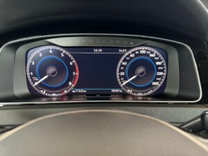 Digitales Armaturenbrett eines Autos, Tachometer und Drehzahlmesser, blau beleuchtet.