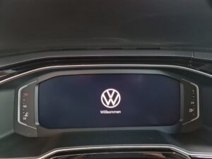 Autodisplay mit Volkswagen-Logo und "Willkommen"-Nachricht. Schwarz mit roten Akzenten.