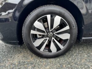 VW-Autoreifen, modern, schwarz-silber Felgen, auf Schotter, Detailaufnahme.