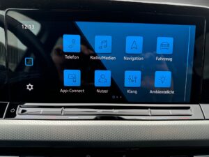 Ein Autodisplay mit blauen App-Symbolen für Telefon, Radio und Navigation, Uhrzeit 12:13.