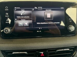 Infotainment-Bildschirm in Auto, zeigt Uhrzeit 11:15, Temperatur 12°C, keine Telefonverbindung.