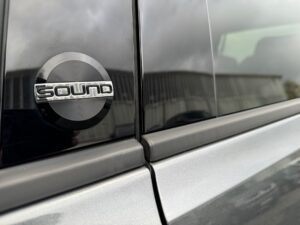 Nahaufnahme eines silbernen Autos mit glänzendem "Sound"-Logo auf der Fenstersäule.