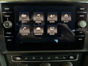 Bildschirm zeigt ein Auto-Infotainment-System mit verschiedenen Optionen und Drehreglern.