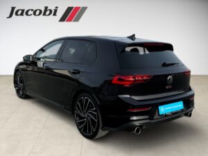 Schwarzer VW Golf GTI, seitliche Rückansicht, sportlich, rote Schrift, Felgen im Doppelspeichen-Design.