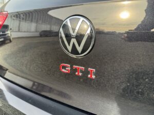 Rückansicht eines schwarzen VW GTI mit gut sichtbarem VW-Logo und roter GTI-Schrift.