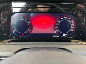 Digitales Armaturenbrett in einem Auto mit roten und schwarzen Anzeigen, Tachometer und Drehzahlmesser.