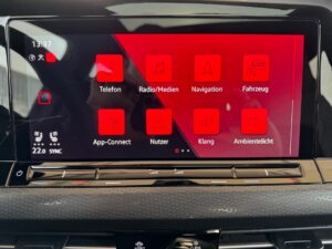 Ein Auto-Bildschirm zeigt Apps: Telefon, Radio/Medien, Navigation, Fahrzeug, App-Connect.