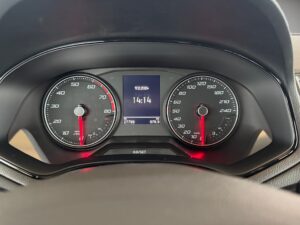 Armaturenbrett eines Autos mit Tachometer und Geschwindigkeitsanzeige, Tachonadeln leuchten rot.