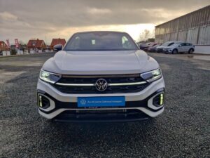 Weißer Volkswagen SUV, Frontansicht, auf Schotterplatz, bei bewölktem Himmel geparkt.