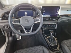 Innenraum eines VW-Fahrzeugs, modern und stilvoll, mit digitalem Bildschirm und Lederlenkrad.