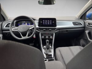 Innenansicht eines VW-Autos, graues Armaturenbrett, schwarzer Sitz und Lenkrad, Touchscreen.