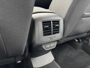 Auto-Innenraum mit schwarzen Sitzen, Lüftungsauslass und USB-Anschlüssen auf der Rückseite.