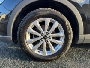 Ein silbernes Audi-Autorad mit Michelin-Reifen auf grauem Kies; blaue Karosserie.