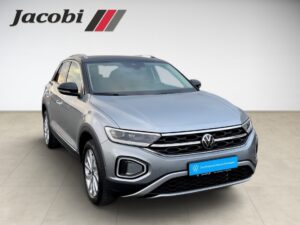 Silberner VW T-Roc mit elegantem Design und markanten Scheinwerfern, Logo "Jacobi" oben links.