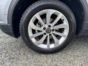 Silberne VW-Felge mit Goodyear-Reifen auf grauem Kies, minimaler Verschleiß.