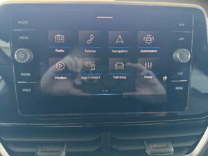 Touchscreen in einem Fahrzeug mit verschiedenen App-Symbolen. Reflexionen sichtbar auf dem Display.