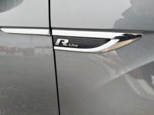 Nahaufnahme eines silbernen Autos mit "R Line"-Emblem auf der Tür.