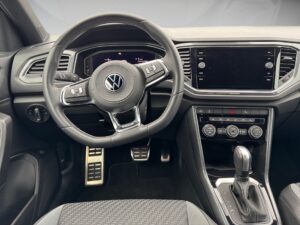 VW-Autoarmaturenbrett in Schwarz, Lenkrad mit Logo, Touchscreen und Bedienelemente erkennbar.