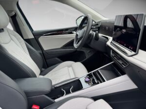 Innenraum eines modernen Autos mit grauen Sitzen, großem Display und schwarzem Lenkrad.