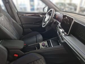 Innenraum eines Autos mit grauen Sitzen, modernem Lenkrad und großem Display, elegantes Design.