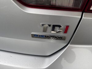 Silbernes Auto mit TDI- und BlueMotion-Technologie-Emblem auf dem Heck bei regnerischem Wetter.