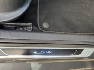 Autositztür mit dem Schriftzug "ALLSTAR" auf Metallplatte, schwarzer Innenraum.