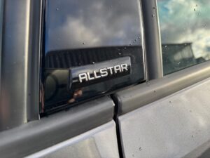 Nahaufnahme eines Autos mit einem "ALLSTAR"-Logo auf glänzendem schwarzen Hintergrund.