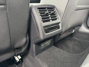 Rückbank eines Autos mit Lüftungsschlitzen und USB-Anschlüssen, schwarze Innenausstattung, detailreich.