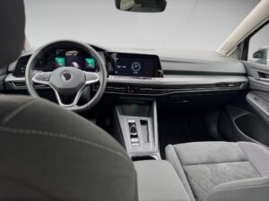 Innenraum eines modernen Autos mit digitalem Armaturenbrett und grauen Polstern.